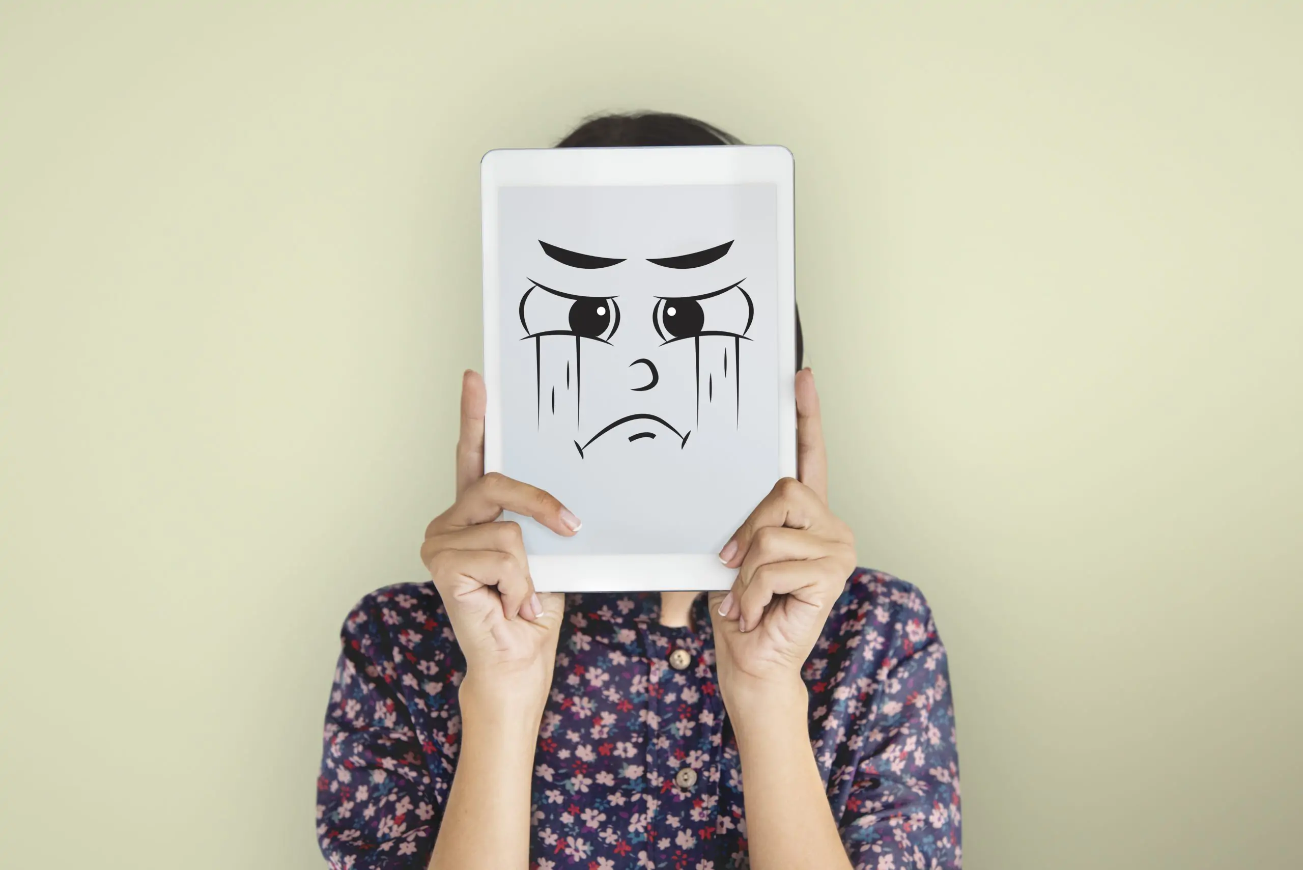 Persona sujetando una imagen de una cara triste