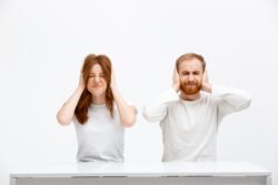 Hombre y mujer tapándose los oídos